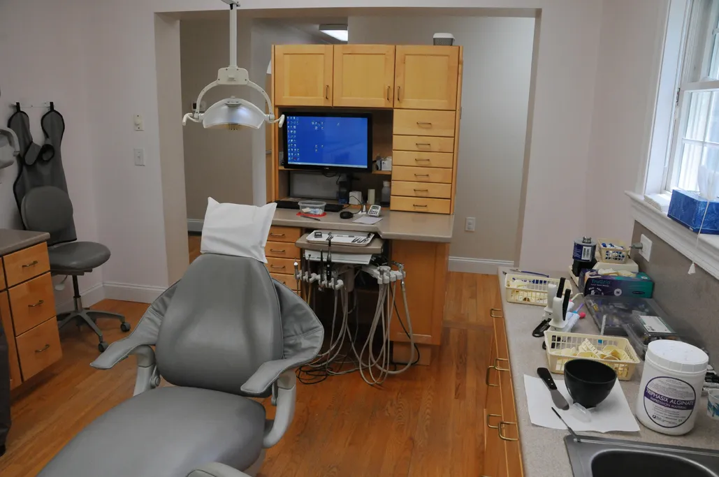 A treatment room with a dental chair and computer