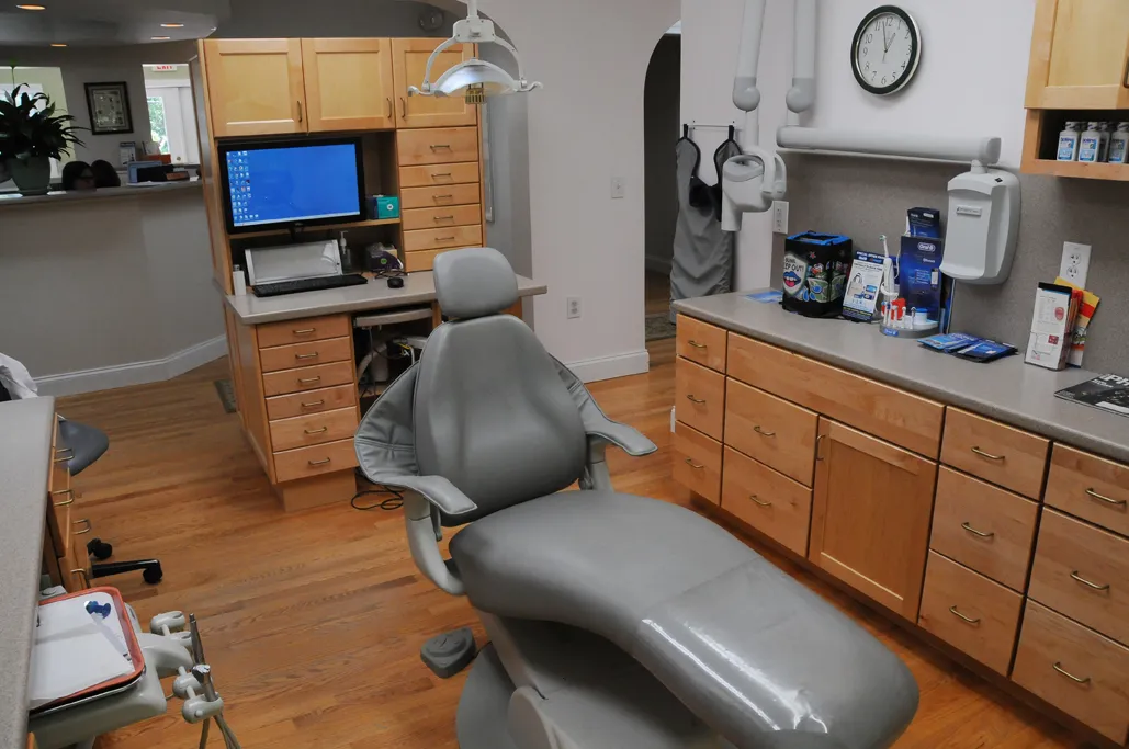 A second treatment room with a dental chair and wood cabinets