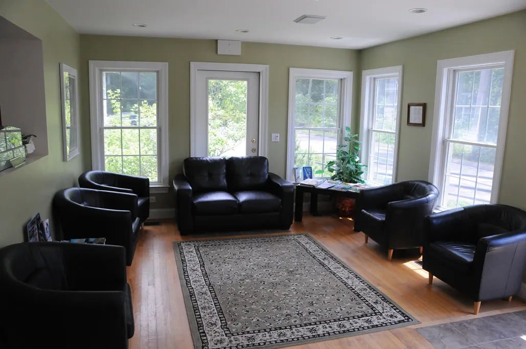 The waiting room with leather chairs and windows onto the trees